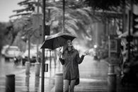 一名女子撑着伞，在城市街道上享受雨天