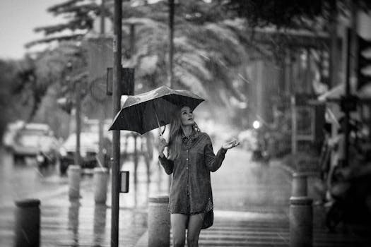 Woman enjoying a rainy day on a city street, holding an umbrella.