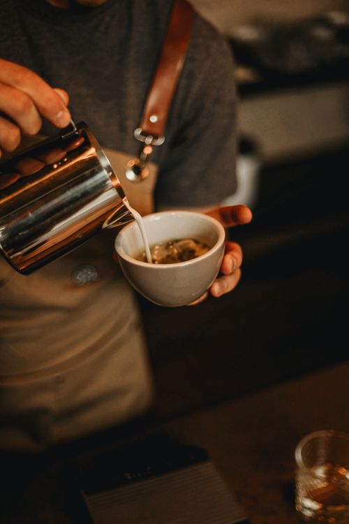 Free A barista skillfully pours steamed milk into a fresh espresso, creating a perfect latte. Stock Photo