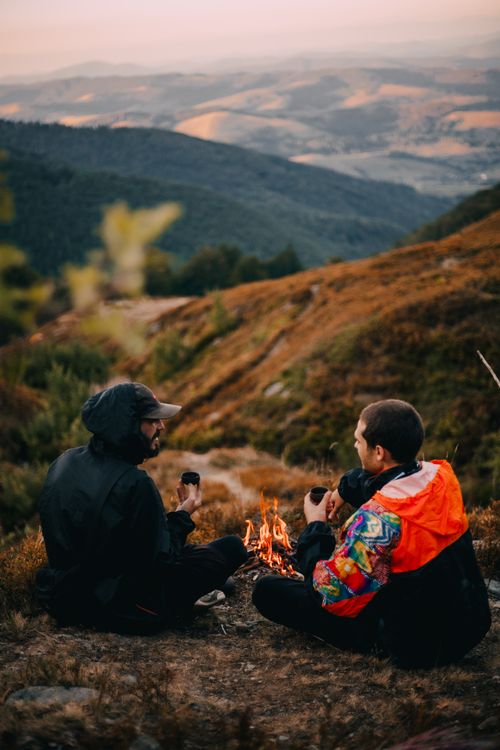 Free Two adults enjoying a campfire on a mountain with scenic views, perfect for outdoor adventure themes. Stock Photo