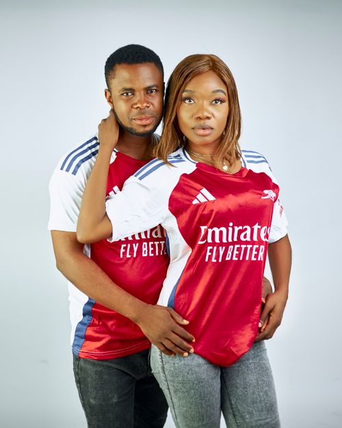 Free A couple poses together wearing matching red and white football jerseys indoors. Stock Photo