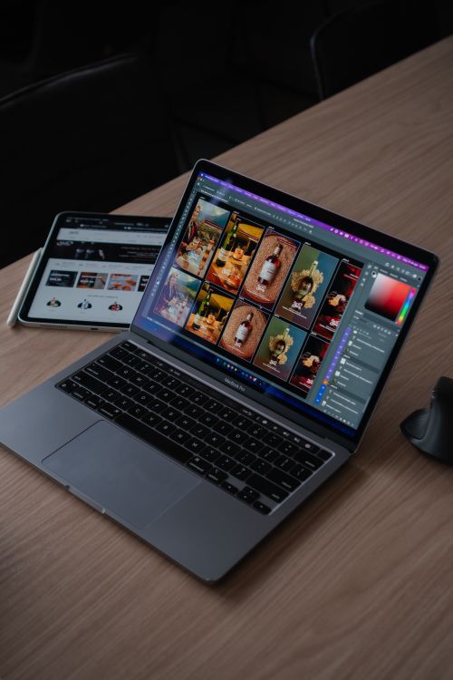 Free A sleek modern workspace featuring a laptop displaying creative design software alongside a tablet. Stock Photo