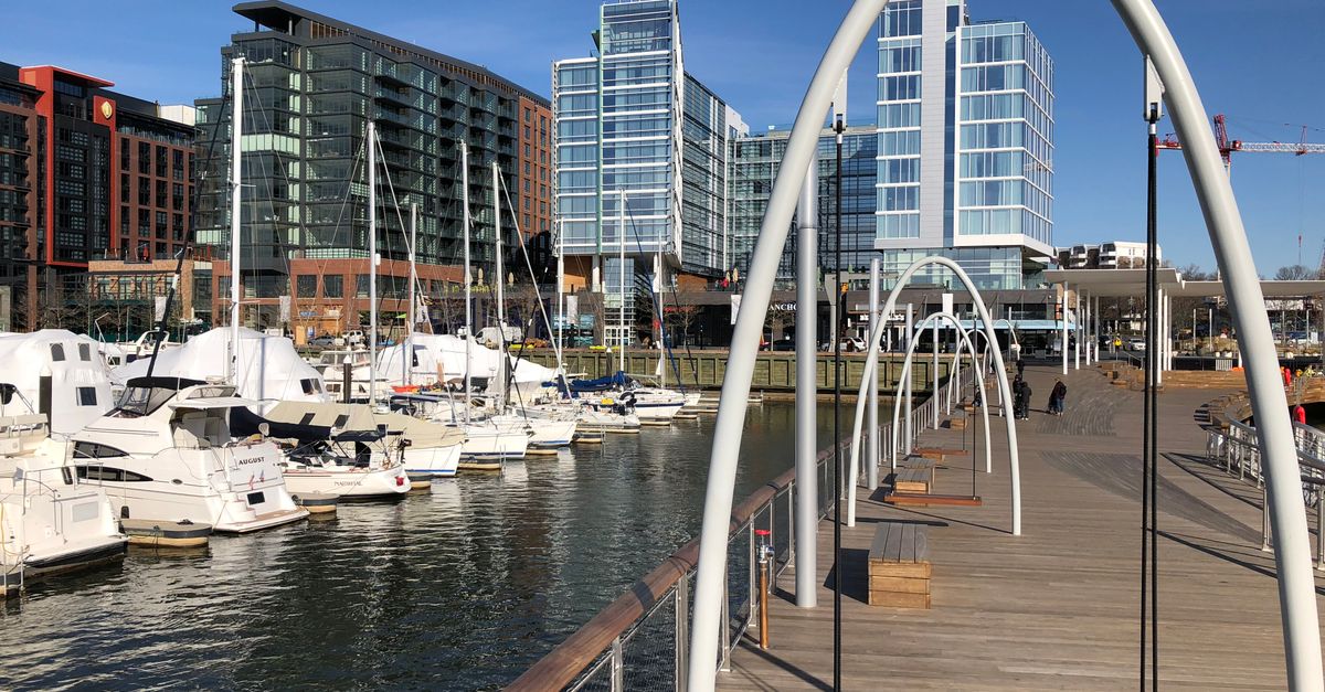 Scenic view of a marina with yachts, modern skyscrapers, and a boardwalk in Washington, D.C.