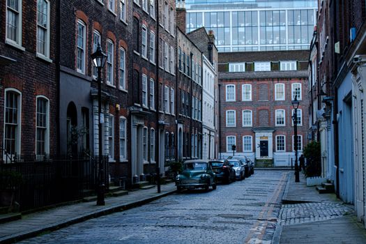 Quaint London street scene featuring historic brick buildings and parked cars, capturing urban charm and architectural elegance.
