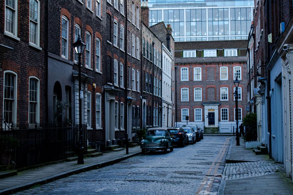 Quaint London street scene featuring historic brick buildings and parked cars, capturing urban charm and architectural elegance.