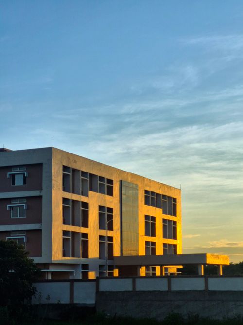 Free A contemporary, minimalist building illuminated by sunset light against a clear sky. Stock Photo