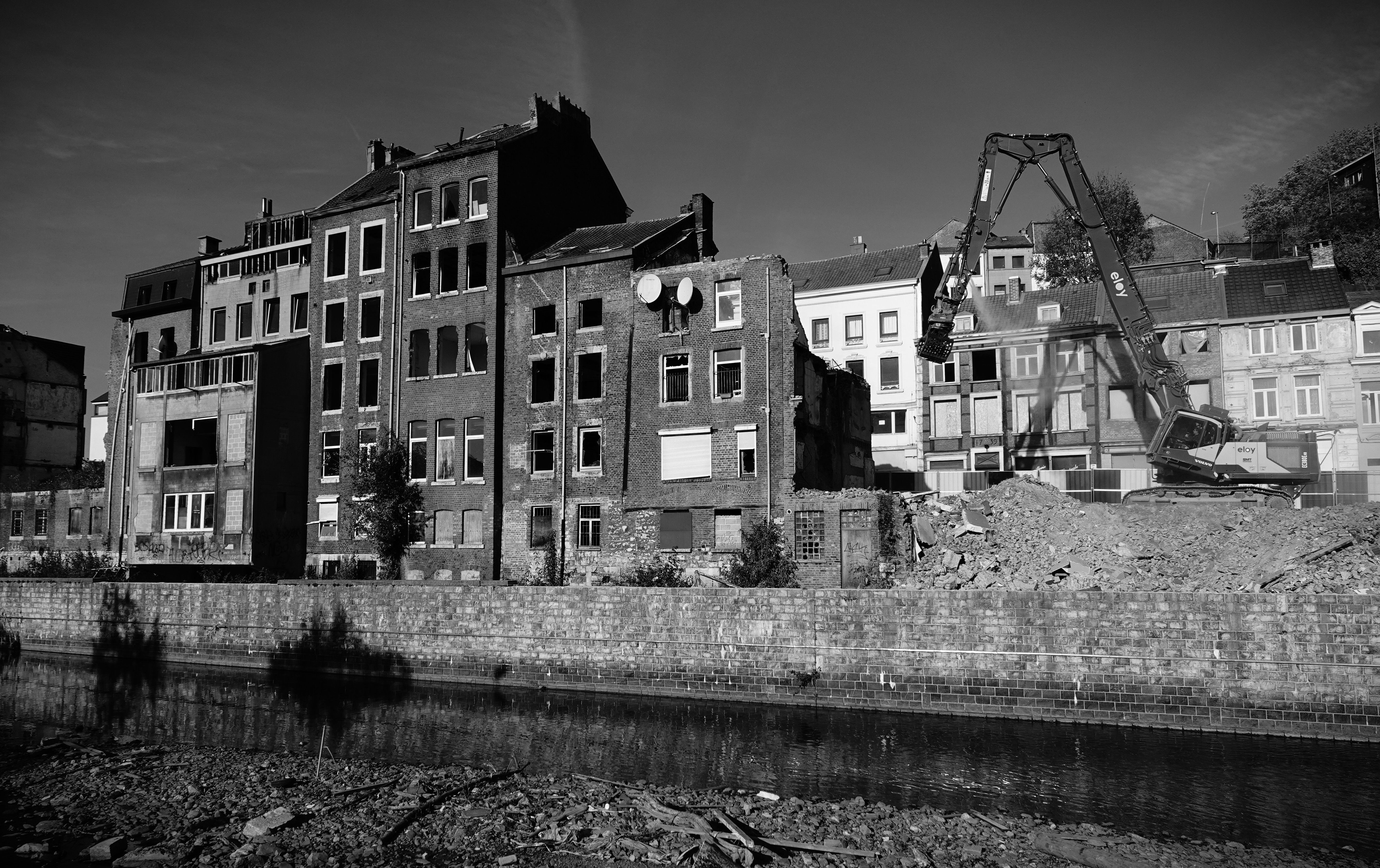 Black and white photo capturing urban redevelopment in Belgium, showing demolished buildings and construction machinery.