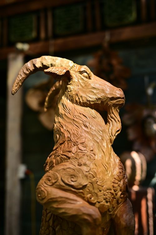 Free Detailed close-up of an artisanal carved wooden goat sculpture under warm ambient lighting. Stock Photo