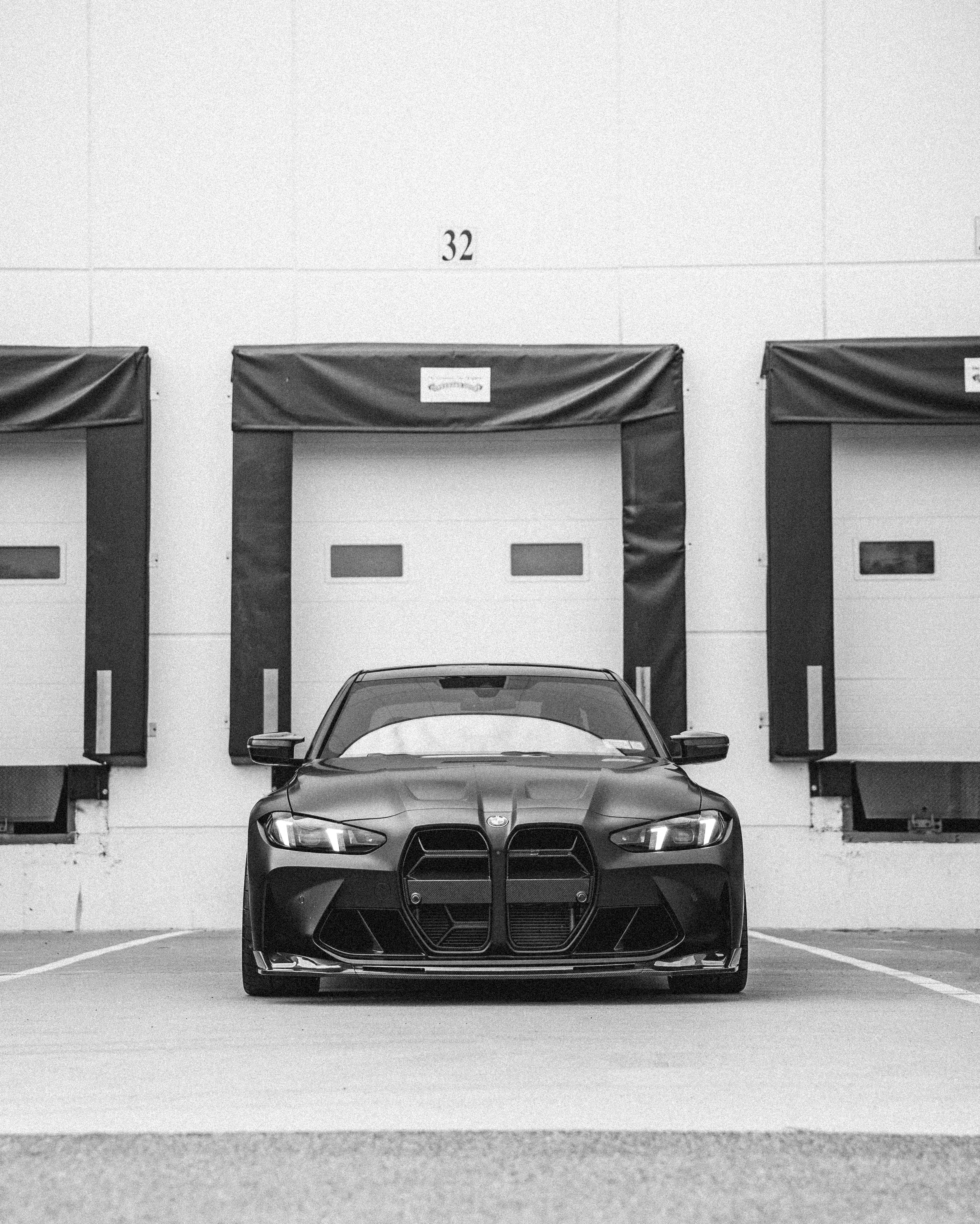 Sleek Black Car Front View in Industrial Setting · Free Stock Photo