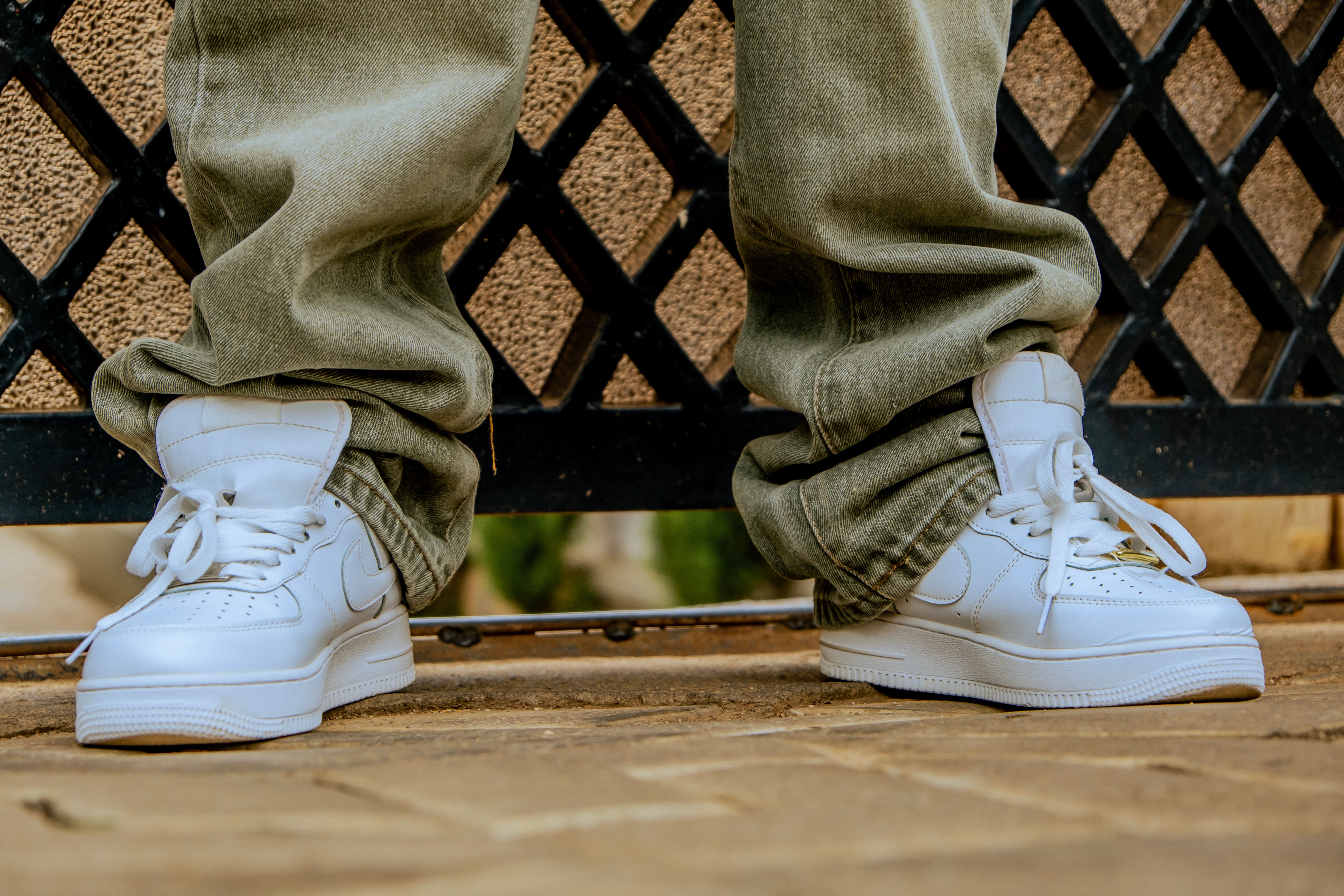 Close-up of white sneakers paired with casual denim jeans on an urban sidewalk.
