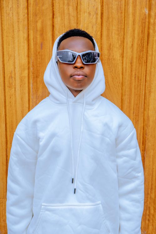 Free A cool, fashionable person wearing a white hoodie and reflective sunglasses against a wooden background. Stock Photo