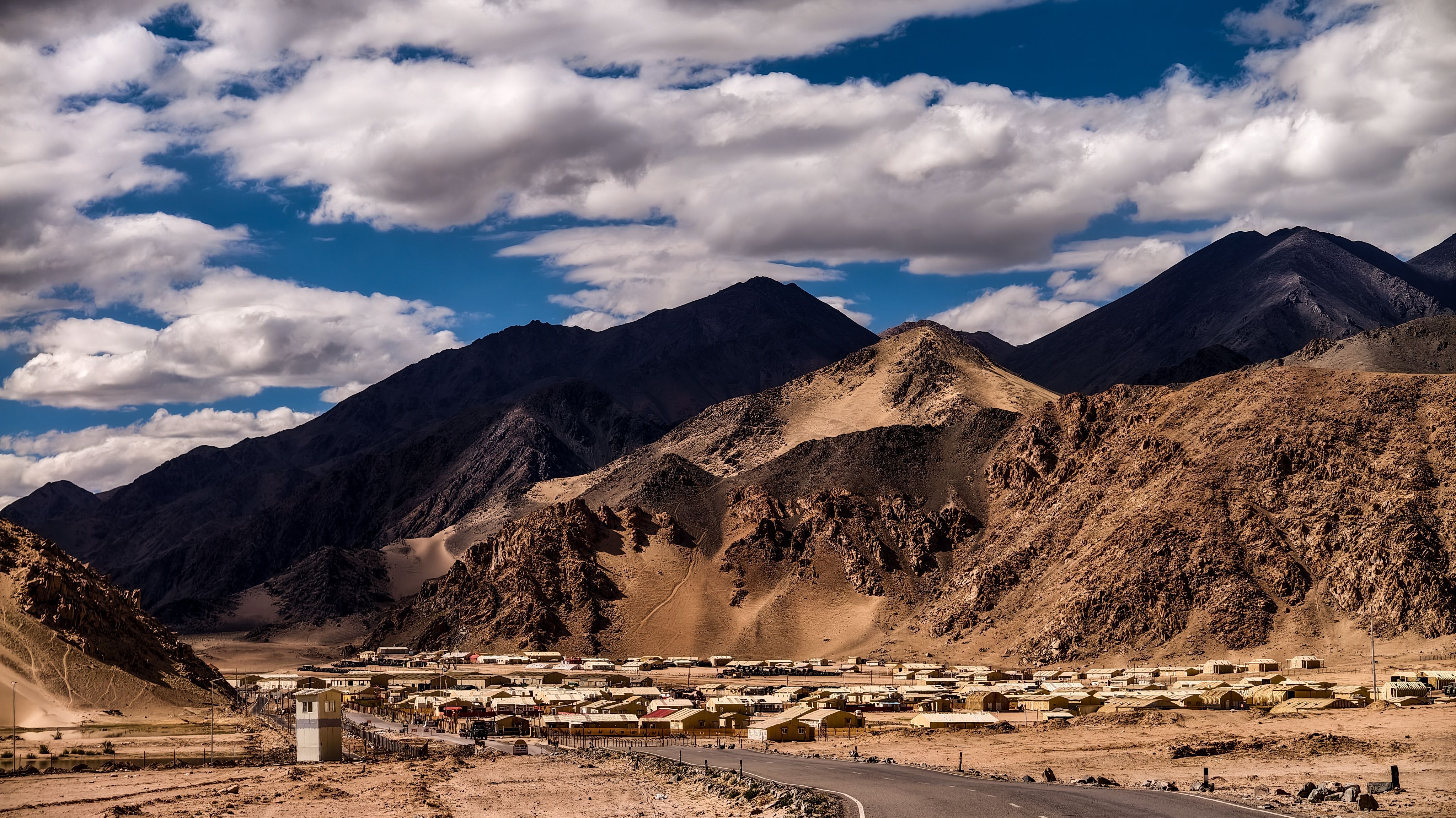 Dramatic landscape of Nyoma village in Ladakh with rugged mountains under a cloudy sky.