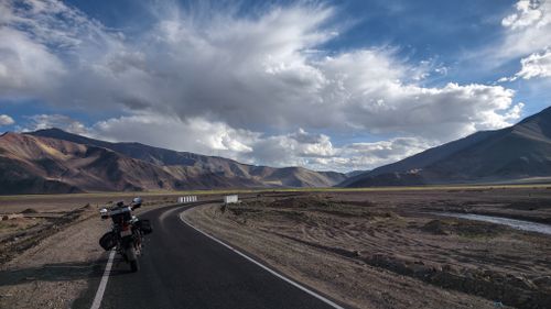 Free Dramatic landscape of a winding road and a motorcycle under a vast sky in Nyoma. Stock Photo