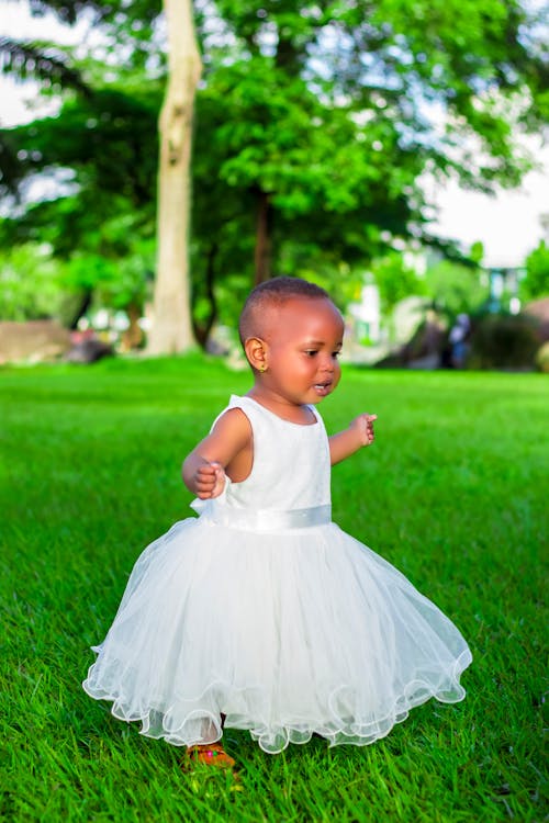 Girl In White Dress Standing On Green Grass 