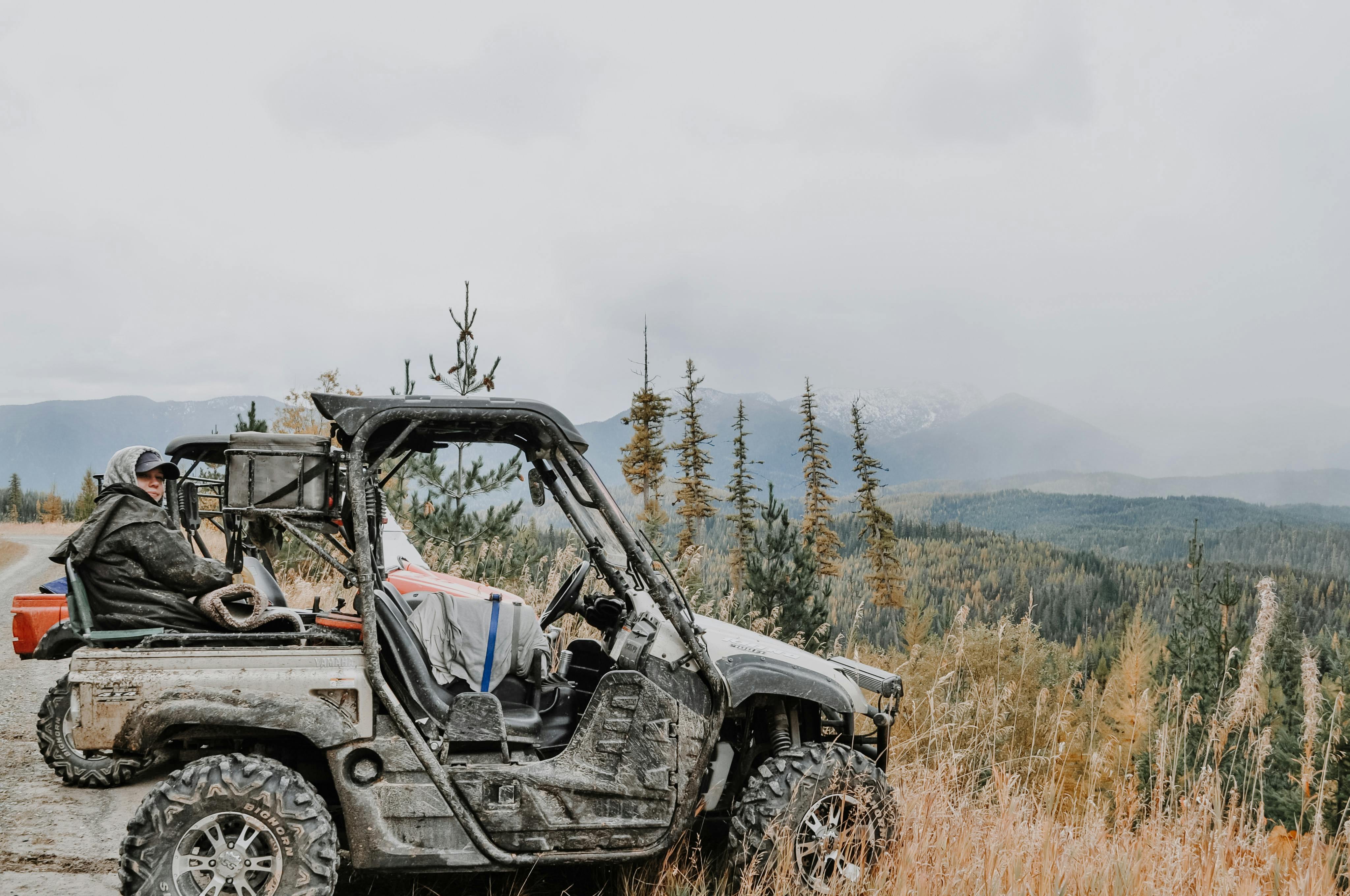 A scenic view of a person driving an all-terrain vehicle through rugged mountainous landscape.