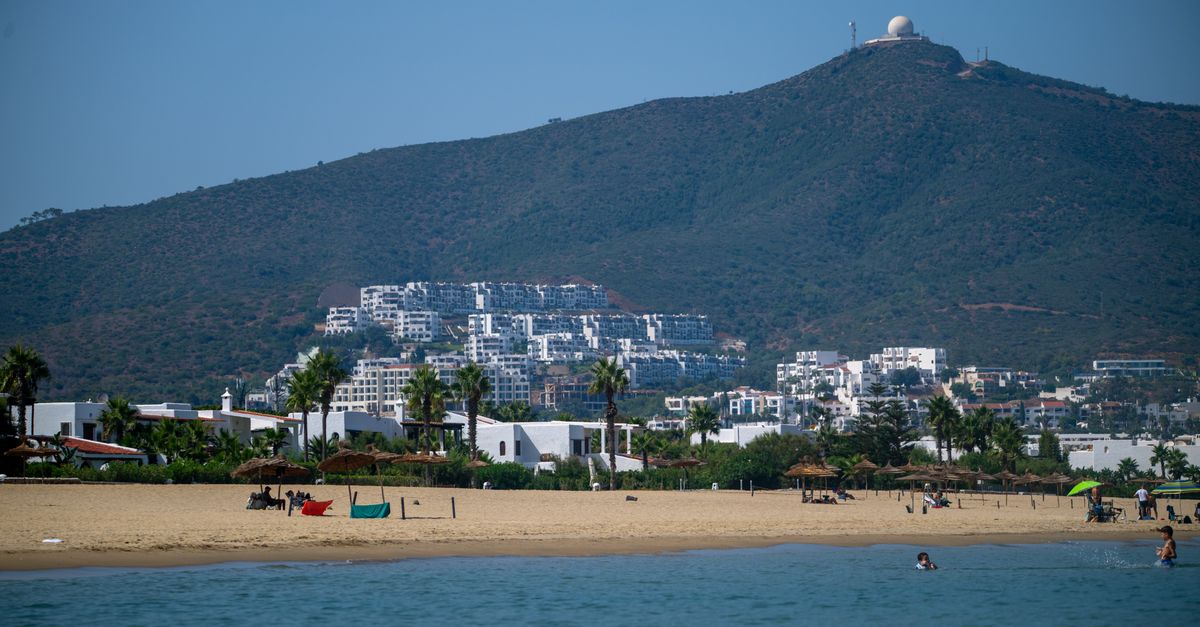A picturesque view of the beach and hillside buildings in Tétouan, Morocco under a clear blue sky.