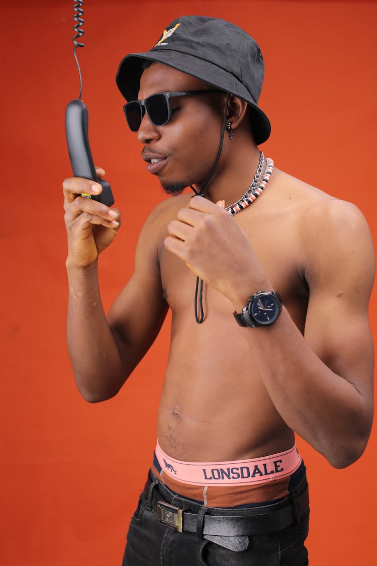 Trendy Black Man Talking On Telephone Handset On Red Background