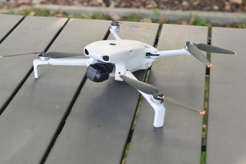 Free A sleek white drone with propellers rests on a wooden table outdoors, ready for flight. Stock Photo