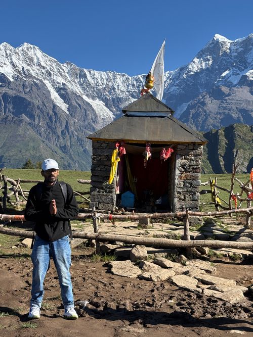 Free Man praying at a mountain temple with stunning Himalayan backdrop under clear skies. Stock Photo