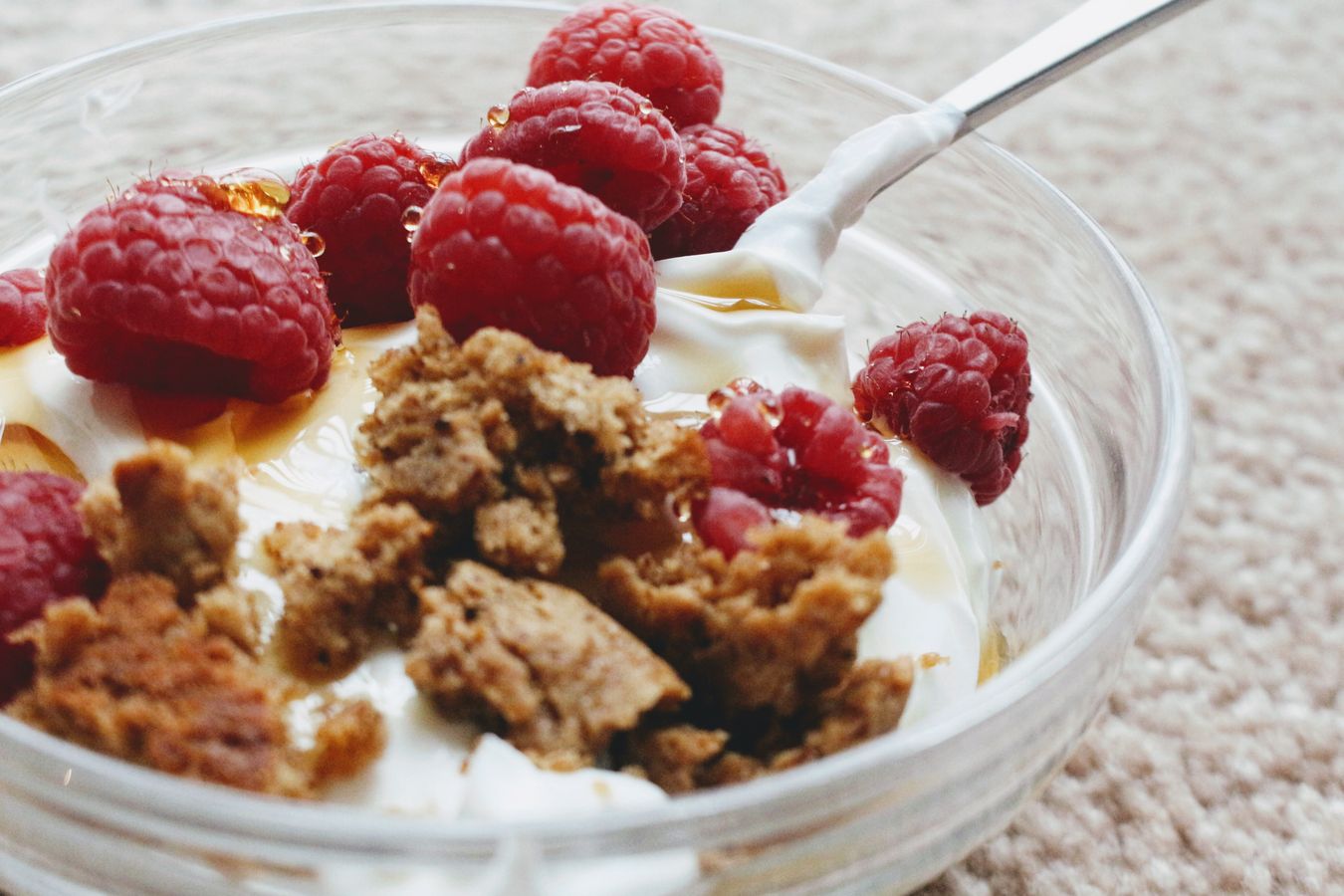 Thick Greek-style yogurt in a bowl with a spoon and raspberries