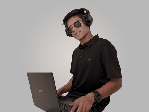 Free A young DJ wearing sunglasses and headphones working on a laptop against a minimalist white background. Stock Photo