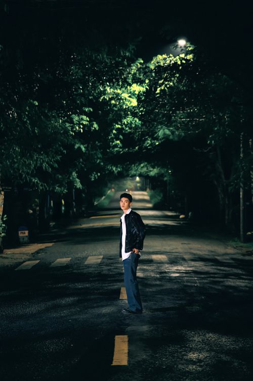 Free A man standing on a dimly lit street in Sa Đéc, creating a mysterious nighttime scene. Stock Photo