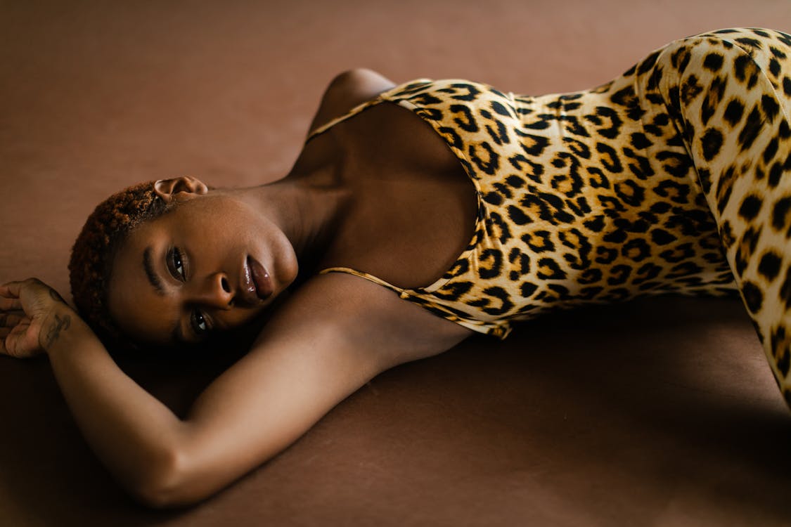 Женщина в комбинезоне с леопардовым принтом, лежа на полу