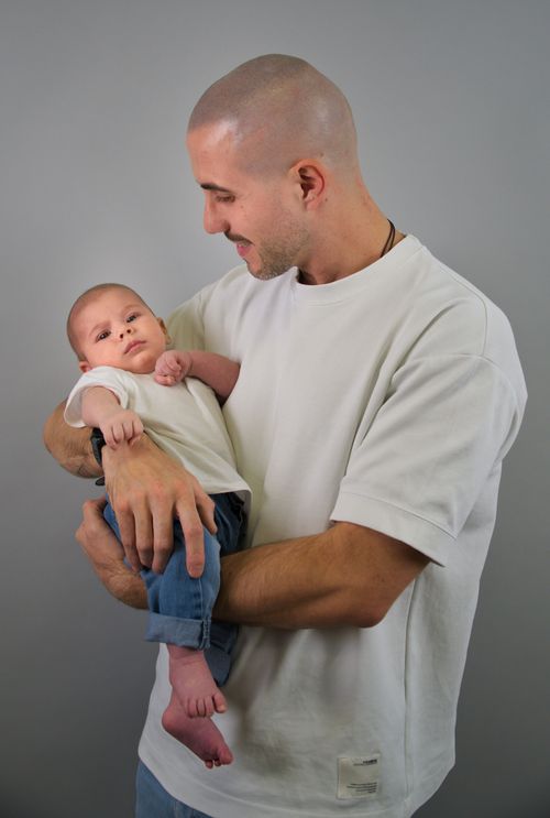 Free A tender moment captured between a father and his newborn baby in a studio setting. Stock Photo