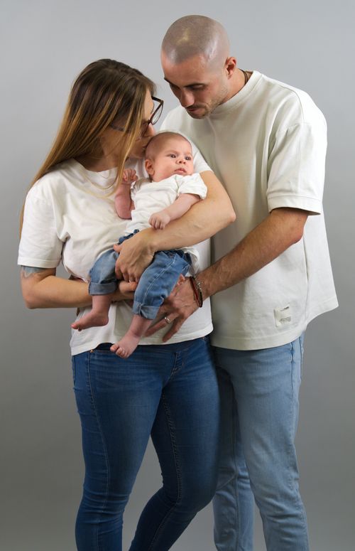 Free Loving family portrait of a couple with their baby in casual attire, indoors. Stock Photo