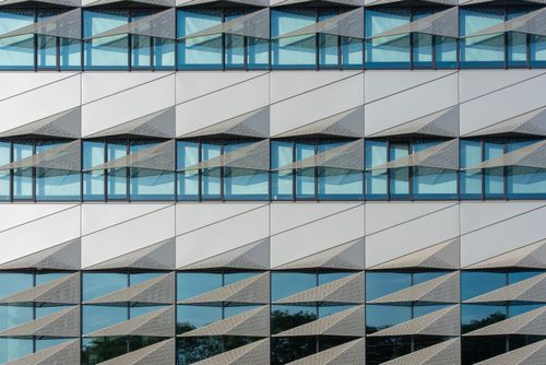 Free Close-up of a modern building facade with geometric design and reflective windows. Stock Photo