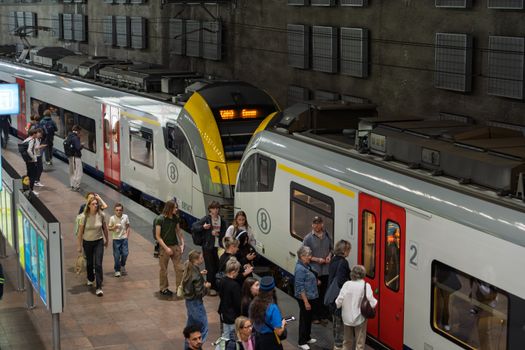 A crowded platform at a train station with people boarding and exiting trains.
