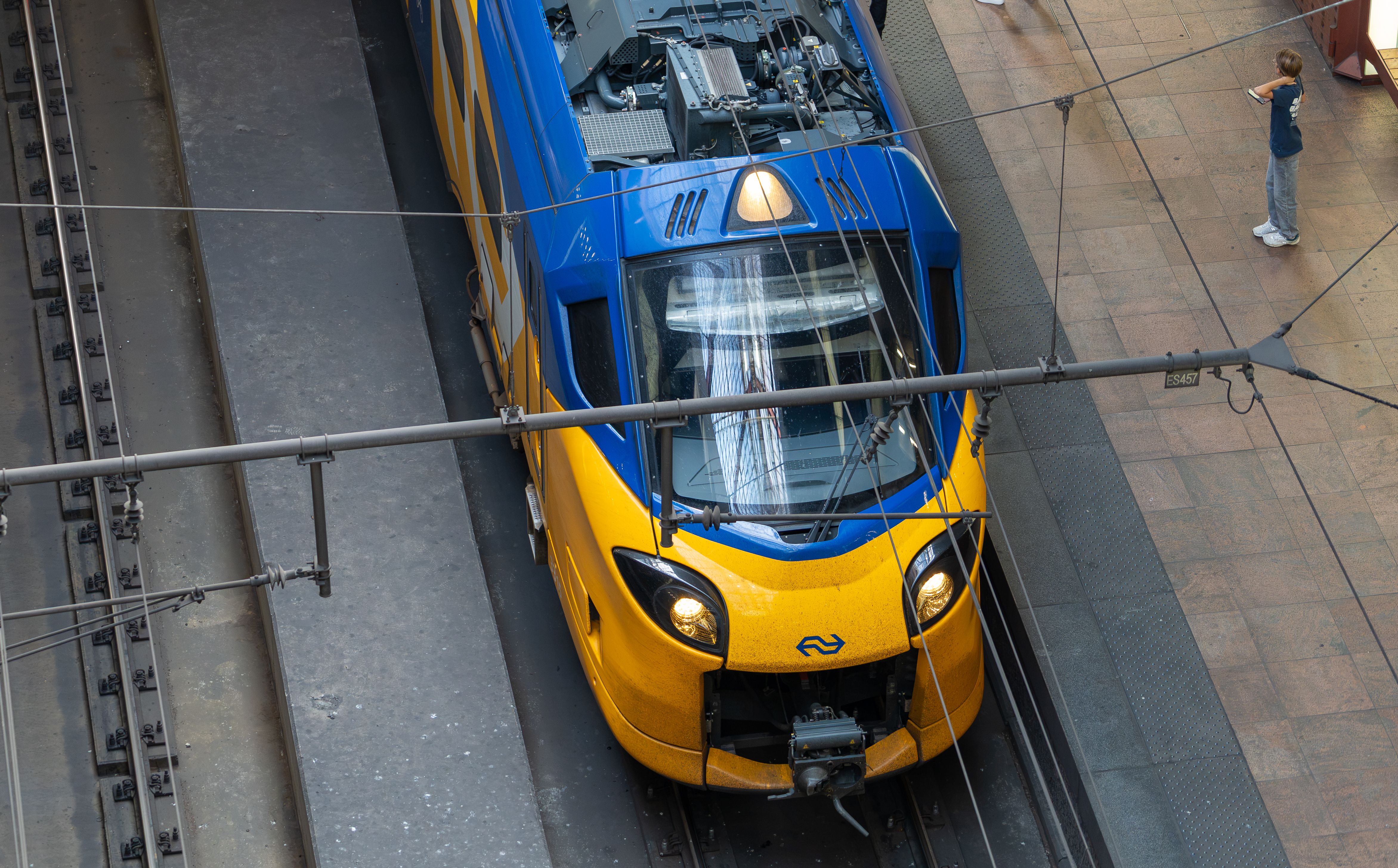 Yellow and blue train viewed from above at a station platform