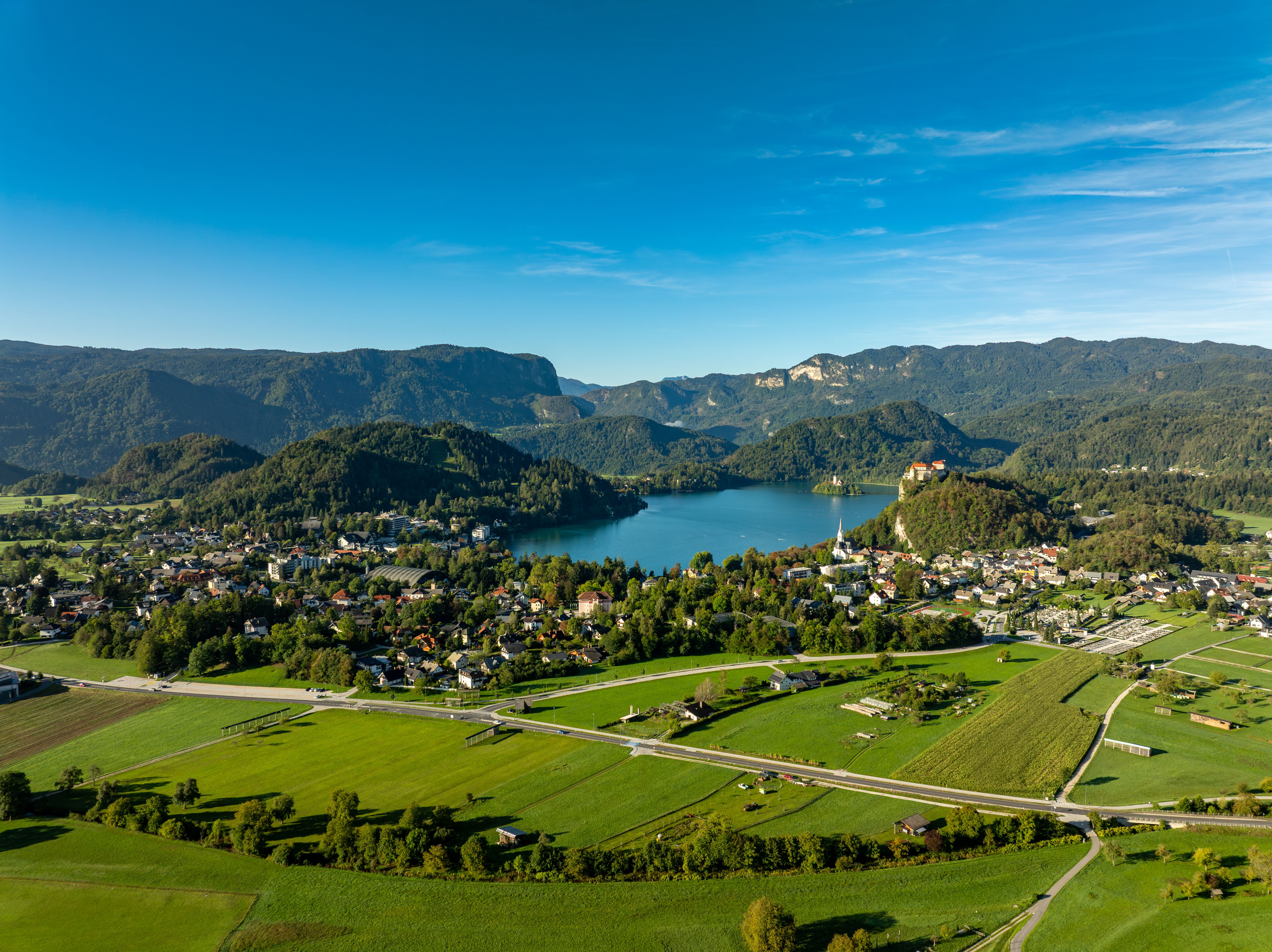 Breathtaking aerial view of Lake Bled and surrounding landscapes in Slovenia, captured on a sunny day.