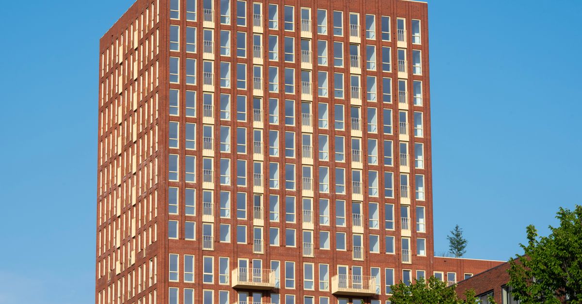 A sleek brick high-rise building against a clear blue sky, depicting modern urban architecture.
