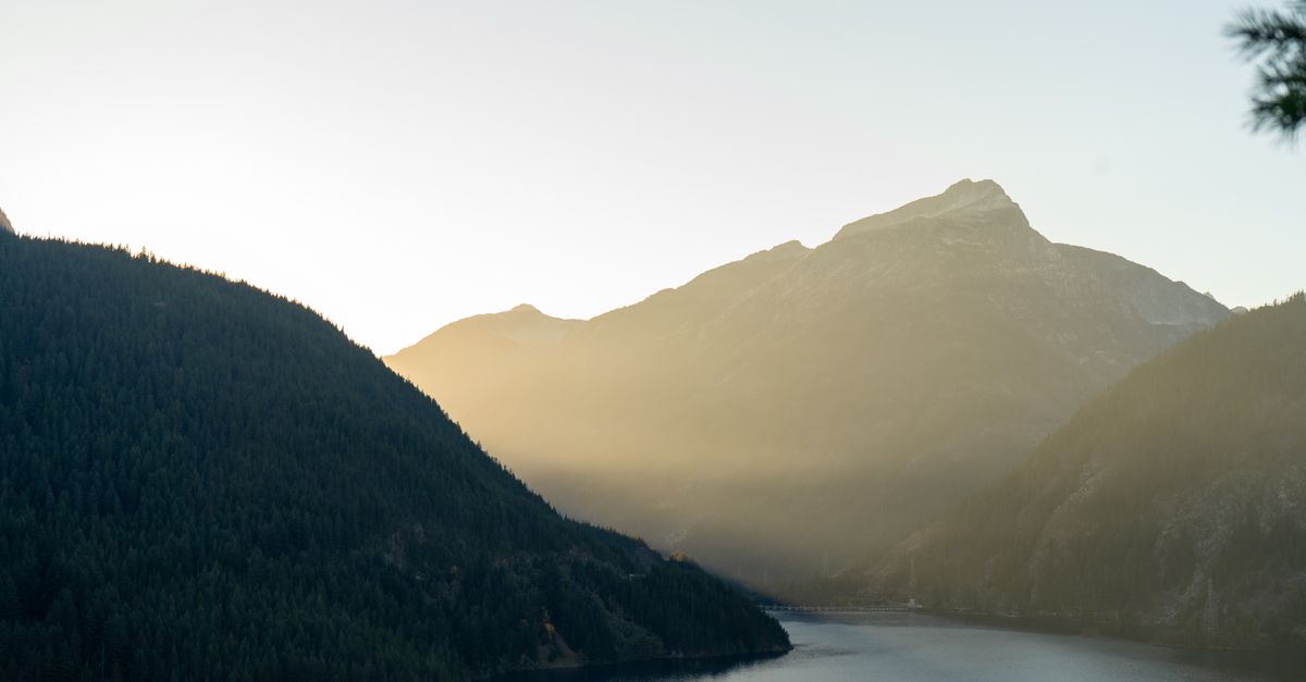 Sunrise over Misty Cascade Mountains with tranquil lake, creating a serene landscape in Washington.