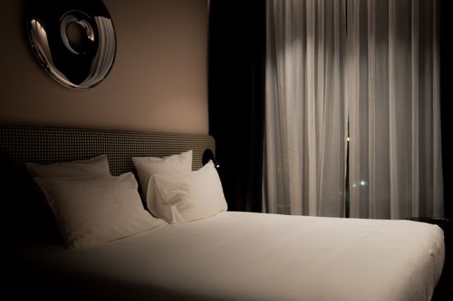 Free An inviting minimalist bedroom with soft lighting, white linens, and elegant decor creating a serene atmosphere. Stock Photo