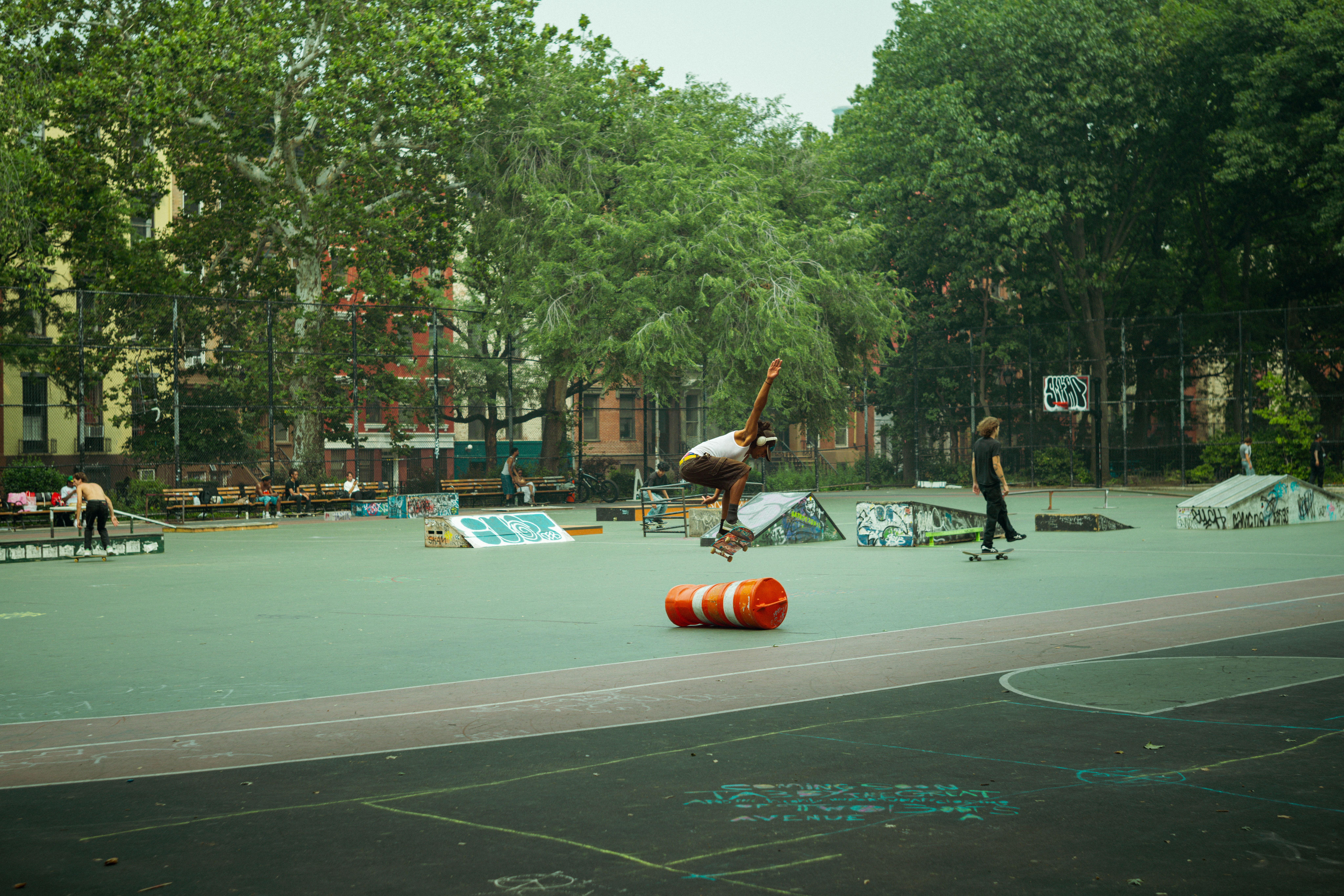 A skateboarder jumps over a traffic cone in Thompson Square Park, NYC.