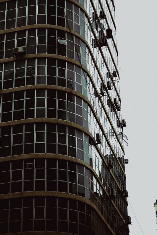 Free Close-up of a modern skyscraper with reflective glass windows in an urban Brazilian setting. Stock Photo