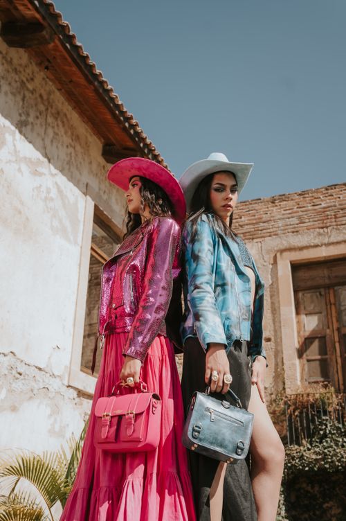 Free Two stylish women in cowboy hats and vibrant outfits pose outside a rustic building. Stock Photo
