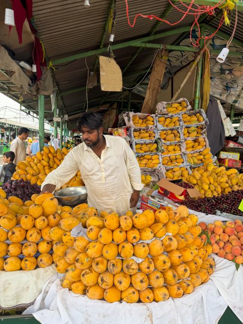 Free A man sells fresh mangoes at a colorful outdoor market, showcasing local produce. Stock Photo