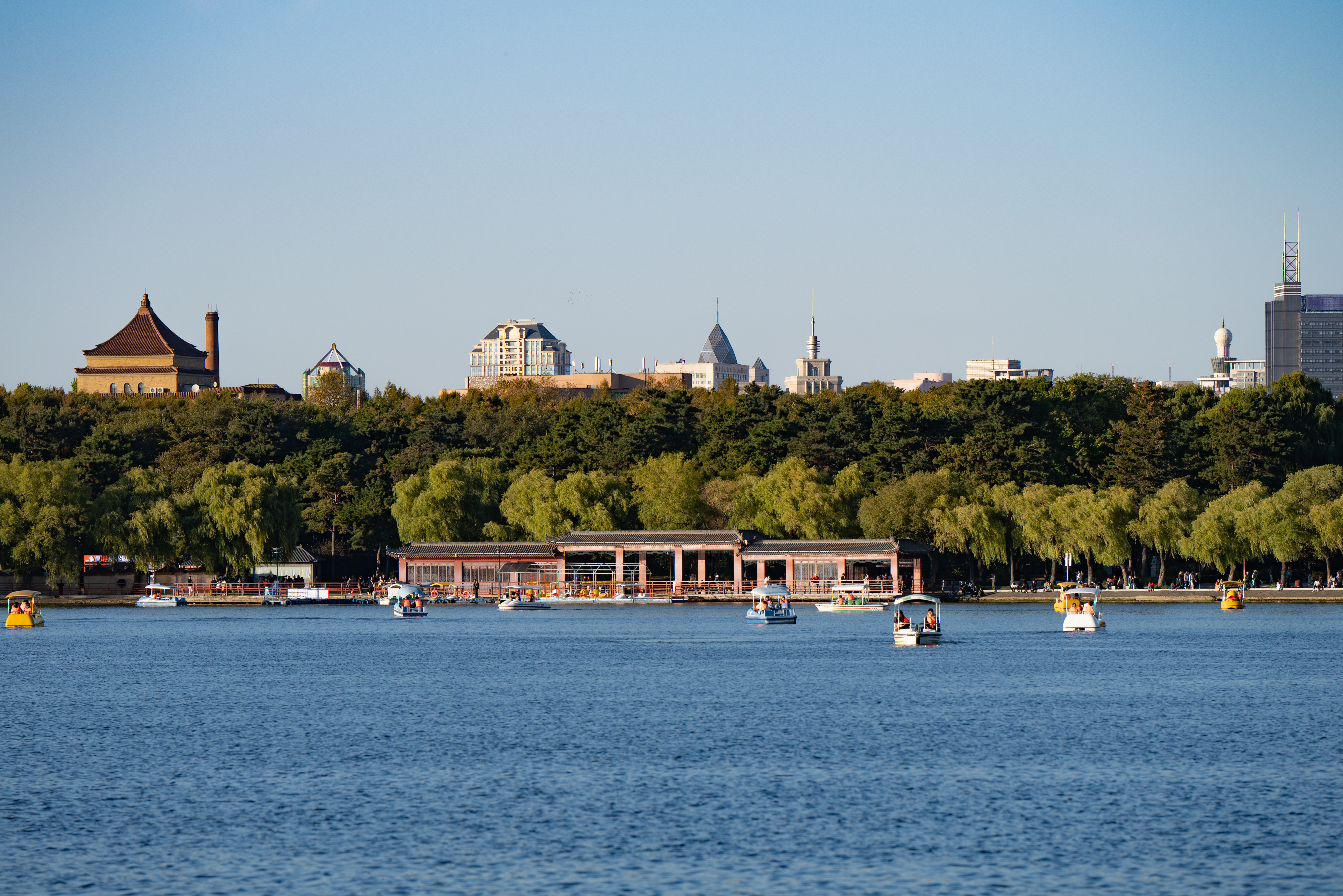 A peaceful lakeside view in Changchun with boats and city skyline in Jilin Province, China.