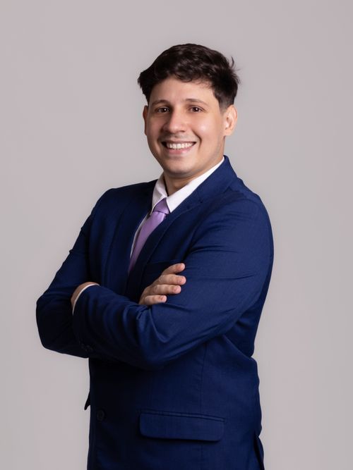 Free Smiling professional posing confidently with crossed arms in elegant blue suit and pink tie. Stock Photo