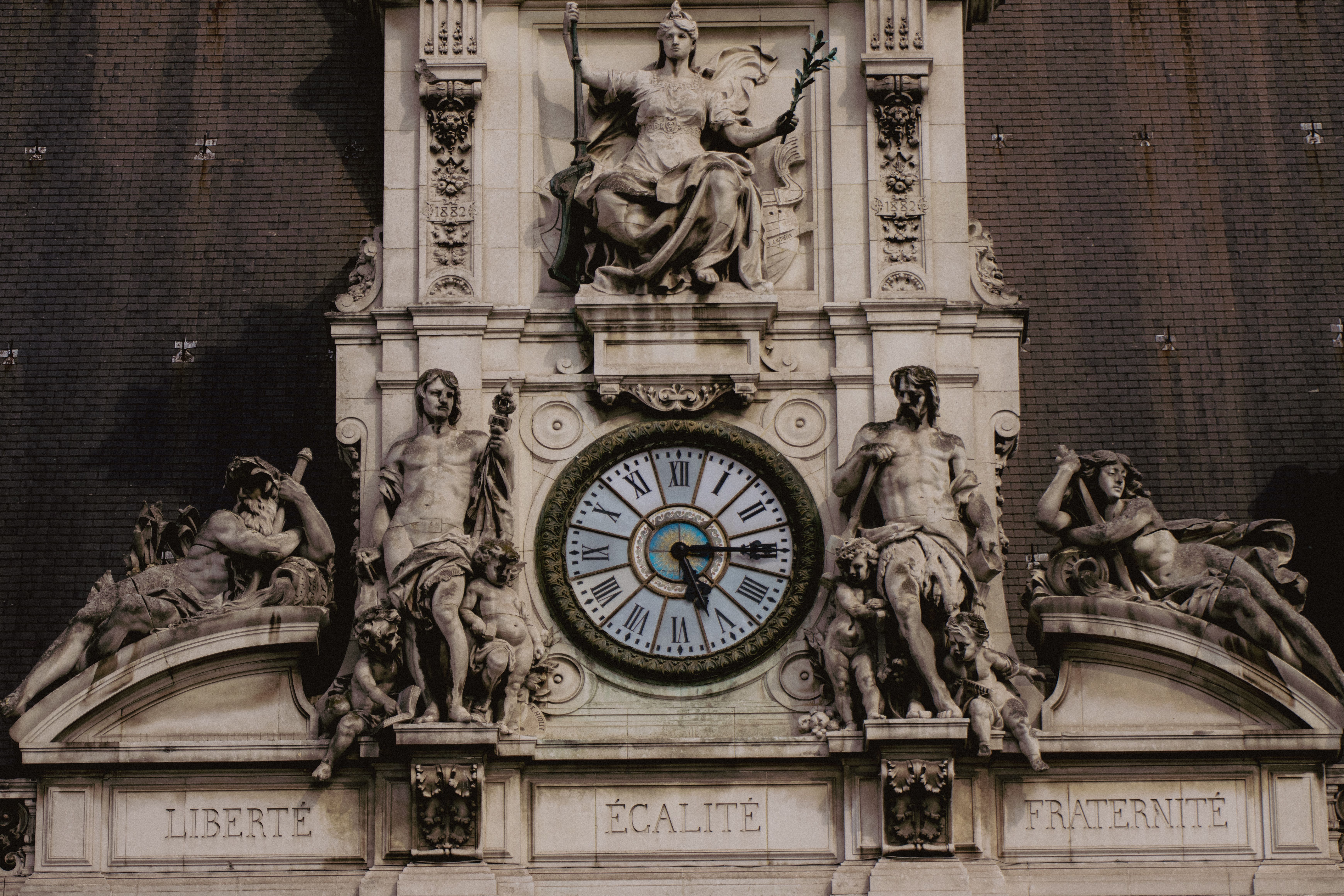 Close-up of the Paris City Hall facade featuring detailed sculptures and a prominent clock, symbolizing French values.
