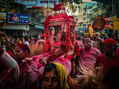 Free Colorful street celebration during Indian festival with people covered in red powder, carrying a decorated shrine. Stock Photo