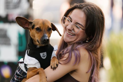 Free Smiling woman holding a small dog outdoors, capturing a moment of joy and companionship. Stock Photo