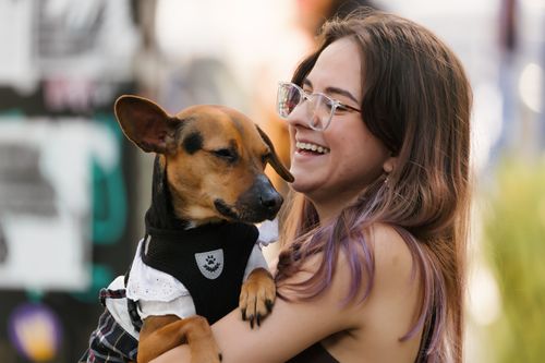 Free A smiling woman embraces her small dog outdoors, capturing a moment of joy and companionship. Stock Photo