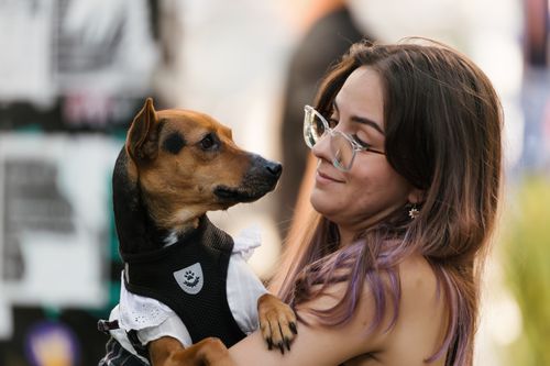 Free A young woman with glasses lovingly holds a small dog outdoors. Stock Photo