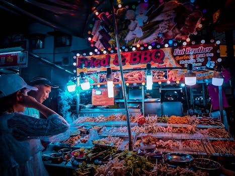 Explore the lively street food scene at a vibrant BBQ stall in Kuala Lumpur's night market.