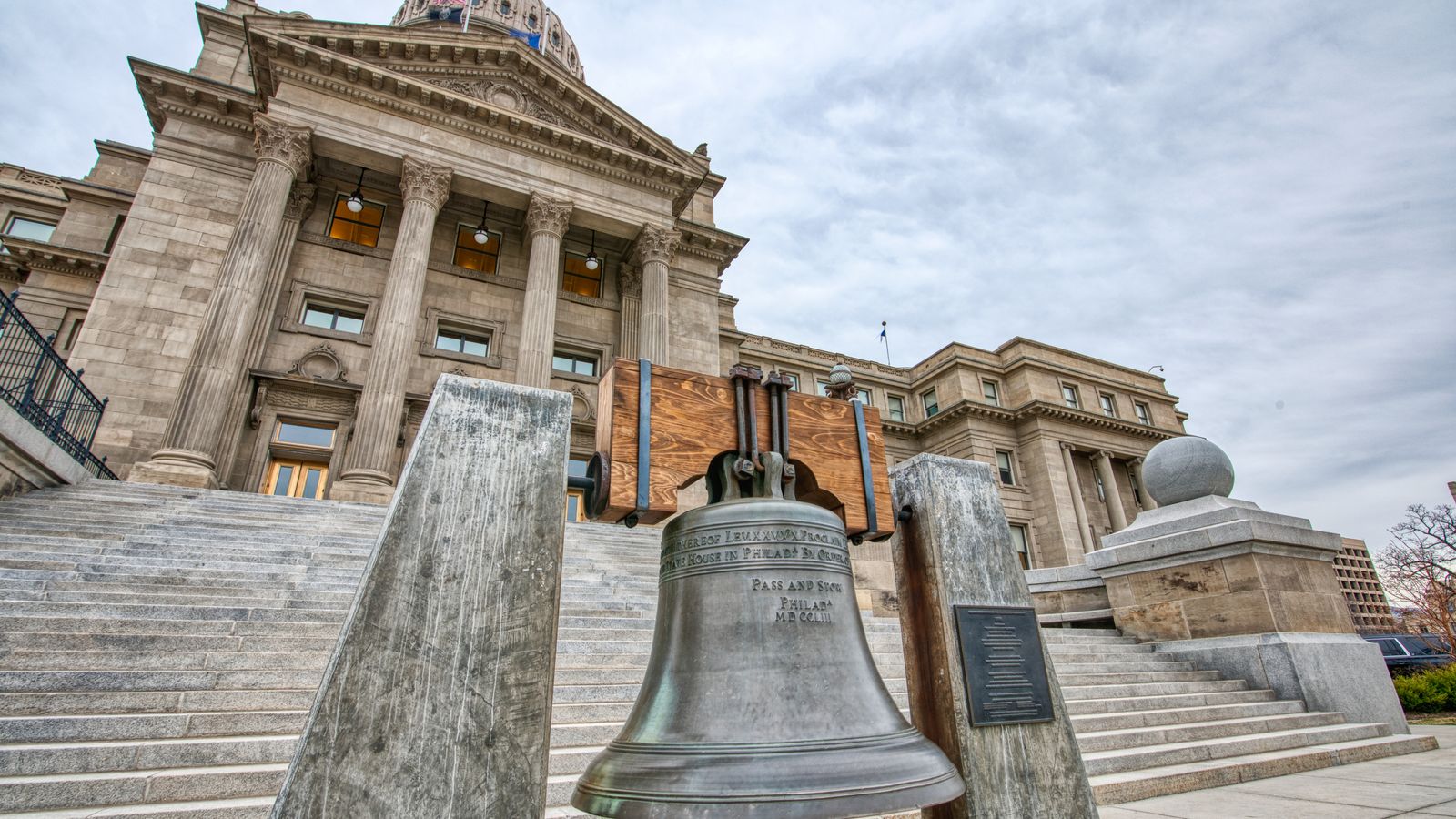 View of a large bell in front of a historic building with classic architectural design.
