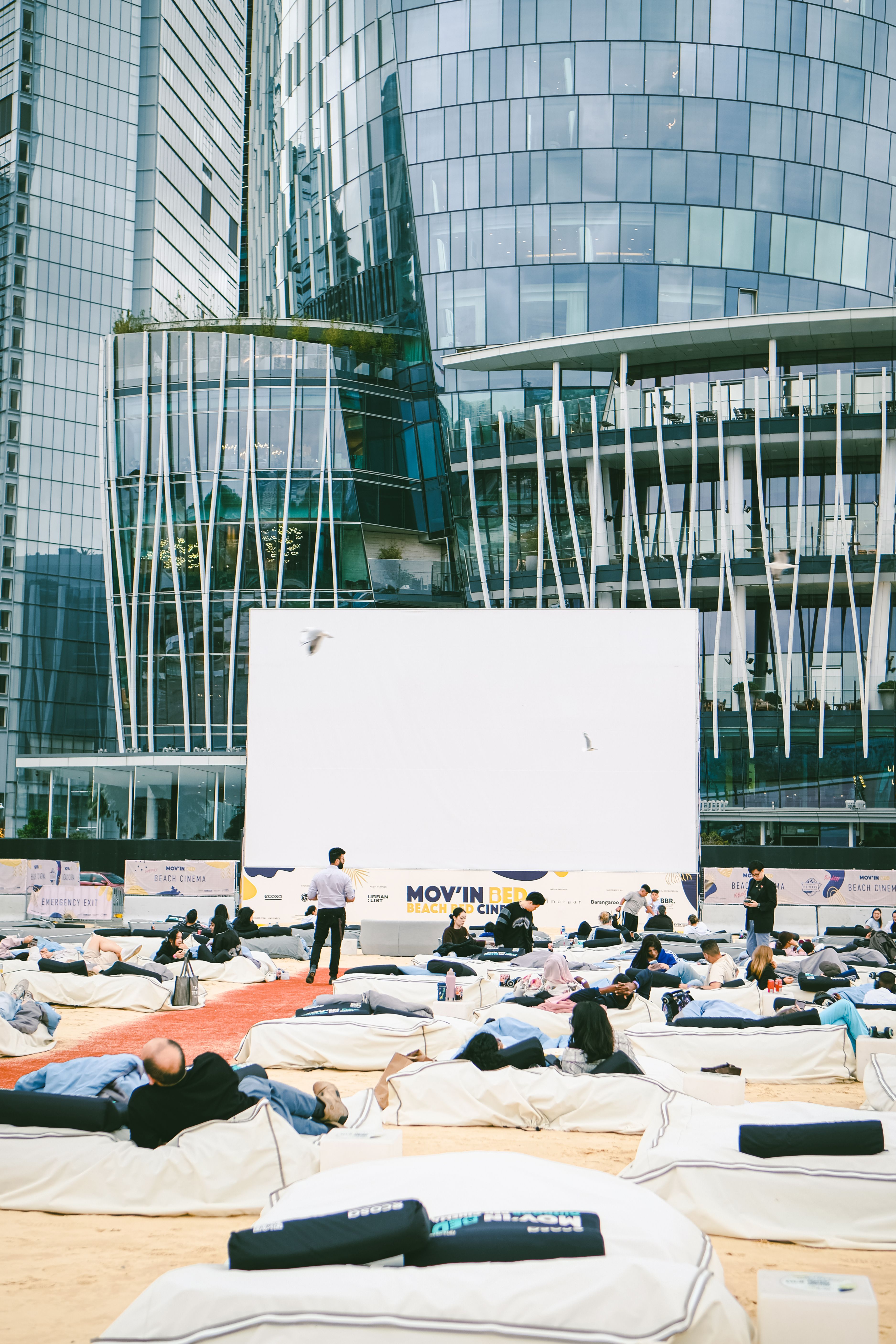 Fotomural Experiencia de cine al aire libre en Barangaroo, con gente relajándose en pufs.